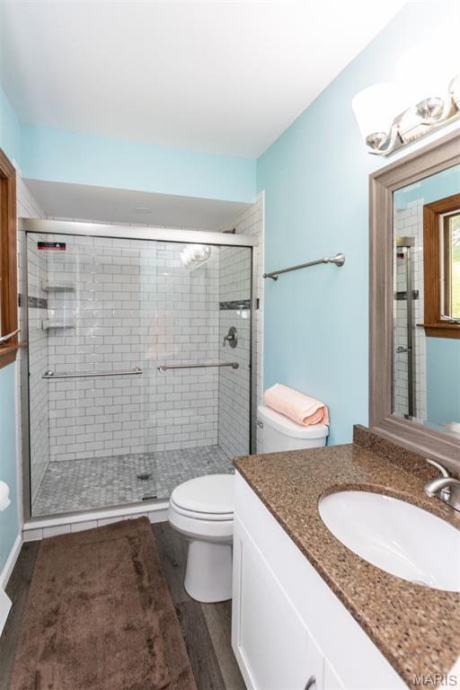 2915 Ozark Dr, Queeny Township, MO 63122 - full bath featuring toilet, vanity, wood finished floors, and a shower stall