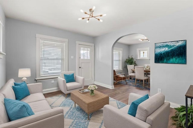 6927 Lansdowne Ave, Saint Louis, MO 63109 - living room with arched walkways, a chandelier, wood finished floors, and baseboards