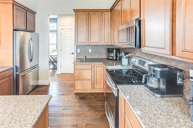 223 Ellington Ct, Glen Carbon, IL 62034 - kitchen with stainless steel appliances, dark wood-style floors, backsplash, light stone counters, and baseboards