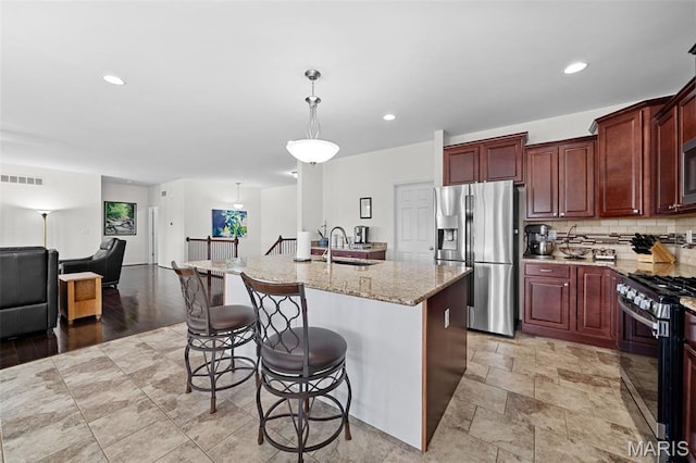 38 Crystal Manor Ct, Wentzville, MO 63385 - kitchen featuring appliances with stainless steel finishes, backsplash, light stone countertops, a kitchen bar, and a sink