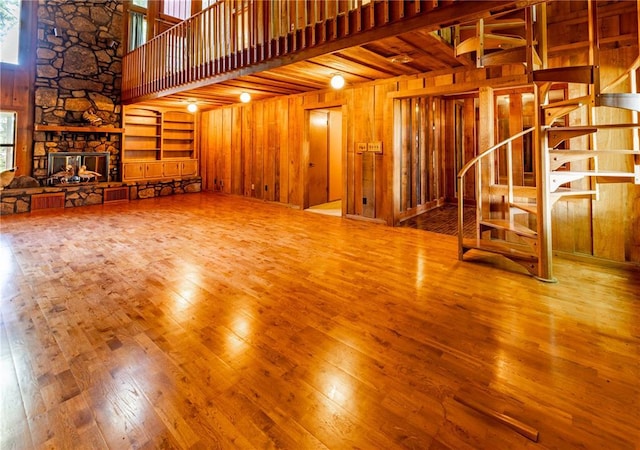 22 Greenbriar Dr, New Madrid, MO 63869 - unfurnished living room with wood walls, hardwood / wood-style flooring, a towering ceiling, stairs, and a fireplace