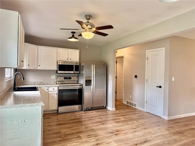 7729 Humbert Rd, Godfrey, IL 62035 - kitchen with appliances with stainless steel finishes, a sink, light wood finished floors, a ceiling fan, and white cabinets