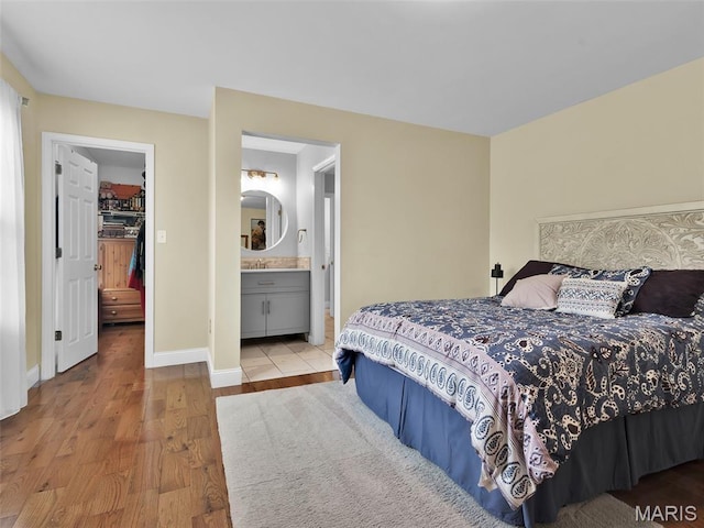1165 Nooning Tree Dr, Chesterfield, MO 63017 - bedroom featuring wood finished floors, a spacious closet, baseboards, and connected bathroom