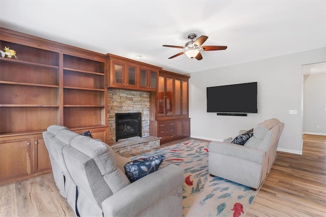 3912 Jacobs Lndg, Saint Charles, MO 63304 - living area featuring ceiling fan, baseboards, a stone fireplace, and light wood-style flooring