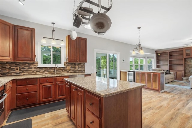 3912 Jacobs Lndg, Saint Charles, MO 63304 - kitchen featuring a sink, light wood-type flooring, open floor plan, backsplash, and decorative light fixtures
