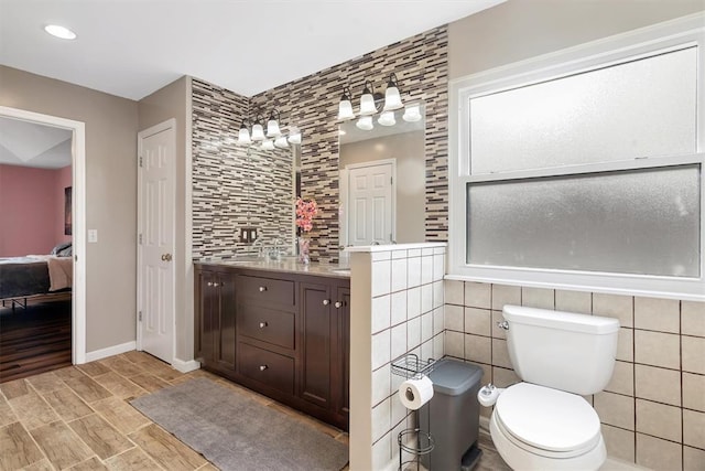 3912 Jacobs Lndg, Saint Charles, MO 63304 - ensuite bathroom featuring tile walls, toilet, wood finish floors, vanity, and baseboards