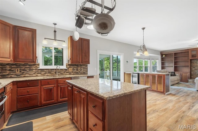 3912 Jacobs Lndg, Saint Charles, MO 63304 - kitchen featuring a sink, light wood-type flooring, open floor plan, decorative backsplash, and hanging light fixtures