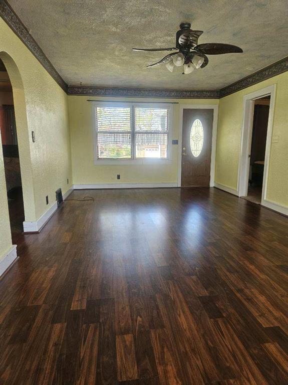 506 S Sparta St, Steeleville, IL 62288 - unfurnished living room with arched walkways, a ceiling fan, baseboards, wood finished floors, and crown molding
