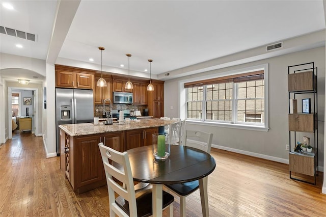 7520 Buckingham Dr Unit 1W, Saint Louis, MO 63105 - kitchen featuring appliances with stainless steel finishes, baseboards, decorative backsplash, arched walkways, and light wood finished floors