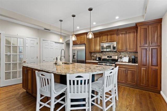 7520 Buckingham Dr Unit 1W, Saint Louis, MO 63105 - kitchen featuring stainless steel appliances, a sink, dark wood-style floors, a breakfast bar area, and tasteful backsplash
