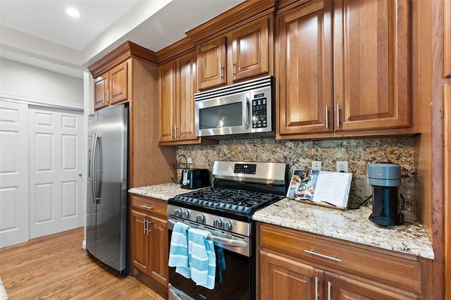 7520 Buckingham Dr Unit 1W, Saint Louis, MO 63105 - kitchen with appliances with stainless steel finishes, brown cabinetry, light stone countertops, decorative backsplash, and light wood finished floors