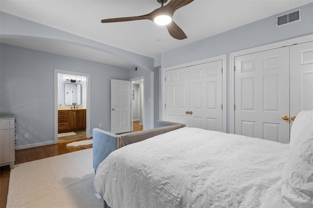 7520 Buckingham Dr Unit 1W, Saint Louis, MO 63105 - bedroom featuring wood finished floors, multiple closets, baseboards, a ceiling fan, and connected bathroom