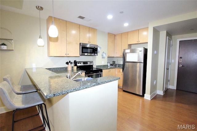 314 N Broadway Unit 603, Saint Louis, MO 63102 - kitchen with appliances with stainless steel finishes, light brown cabinetry, a peninsula, light wood-style flooring, and light stone countertops