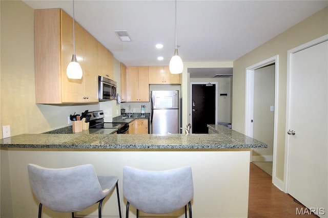 314 N Broadway Unit 603, Saint Louis, MO 63102 - kitchen featuring stainless steel appliances, a peninsula, light brown cabinetry, dark wood finished floors, and stone counters