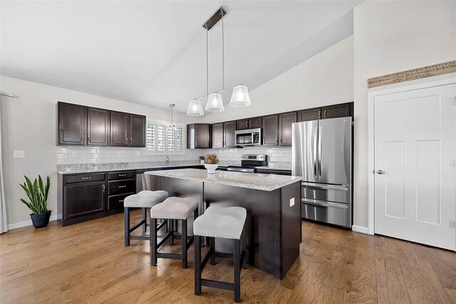 217 Arlington Dr, Moscow Mills, MO 63362 - kitchen with stainless steel appliances, decorative backsplash, a center island, dark brown cabinets, and high vaulted ceiling