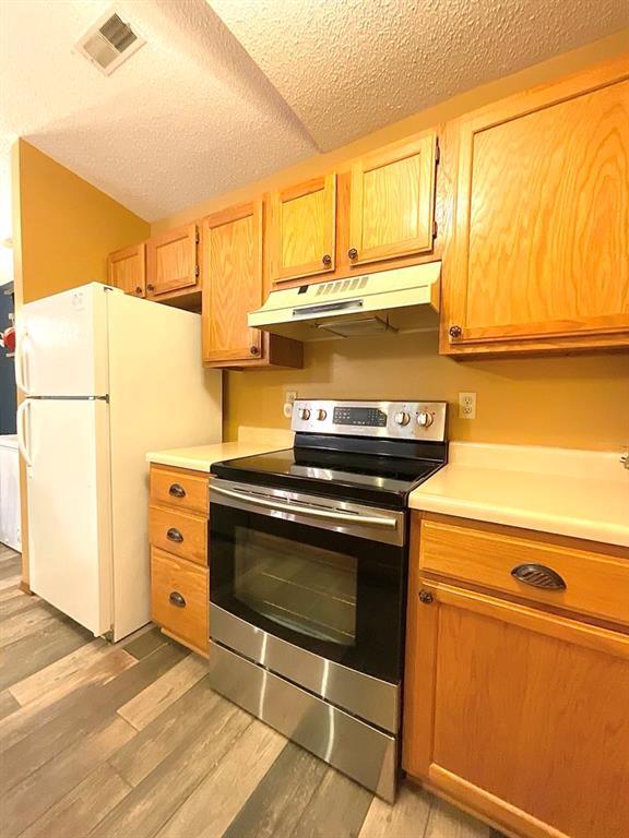 18318 Lakeview Cir Unit 606, Monroe City, MO 63456 - kitchen featuring electric stove, under cabinet range hood, light countertops, light wood finished floors, and a textured ceiling