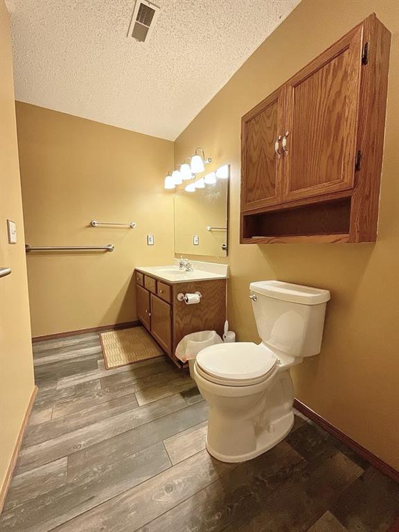 18318 Lakeview Cir Unit 606, Monroe City, MO 63456 - bathroom with a textured ceiling, toilet, wood finished floors, baseboards, and vanity