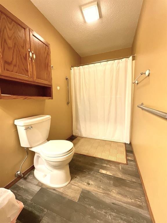 18318 Lakeview Cir Unit 606, Monroe City, MO 63456 - full bathroom featuring a textured ceiling, wood finished floors, toilet, a shower with curtain, and baseboards