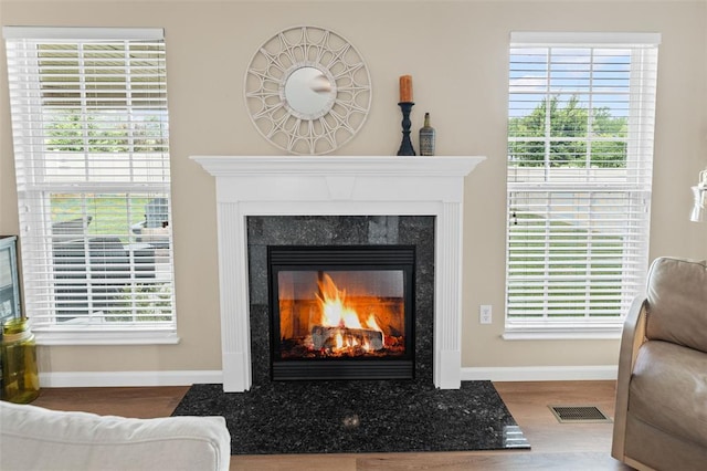 detailed view of a high end fireplace, wood finished floors, and baseboards