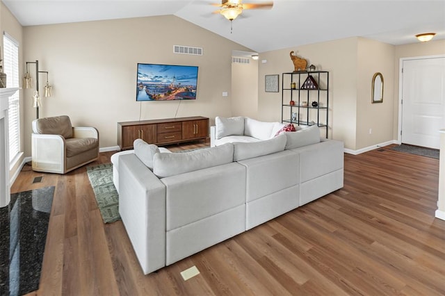 living area featuring ceiling fan, lofted ceiling, wood finished floors, baseboards, and a fireplace