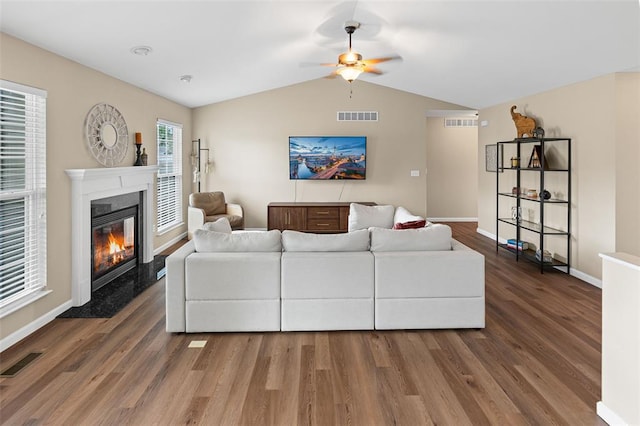 living room with wood finished floors, lofted ceiling, ceiling fan, a fireplace, and baseboards