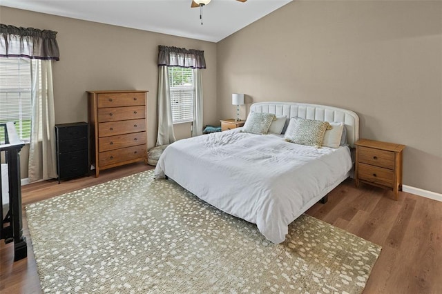 bedroom with wood finished floors, vaulted ceiling, ceiling fan, and baseboards