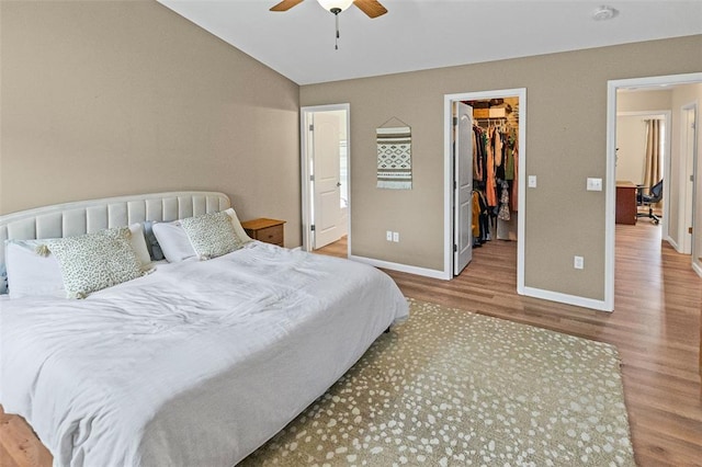 bedroom featuring wood finished floors, baseboards, a spacious closet, a closet, and ceiling fan
