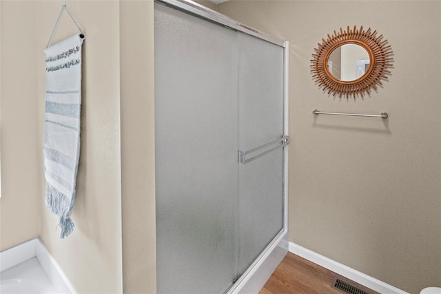 bathroom with a stall shower, wood finished floors, and baseboards