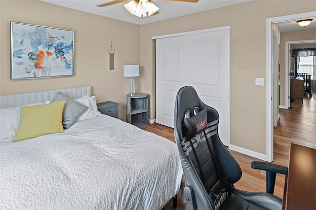 bedroom featuring a closet, wood finished floors, baseboards, and a ceiling fan
