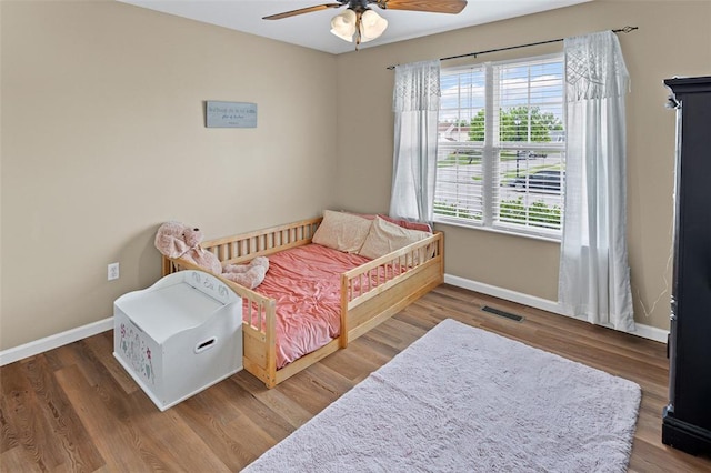 bedroom featuring baseboards, wood finished floors, and ceiling fan