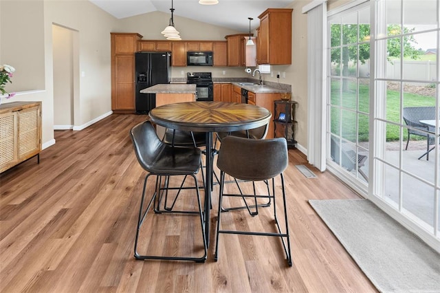 kitchen with black appliances, brown cabinetry, lofted ceiling, a sink, and baseboards