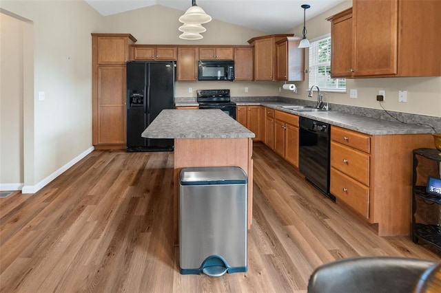 kitchen featuring black appliances, a sink, vaulted ceiling, light wood-type flooring, and hanging light fixtures