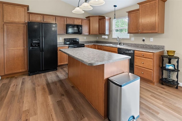kitchen with black appliances, wood finished floors, a sink, brown cabinetry, and a center island