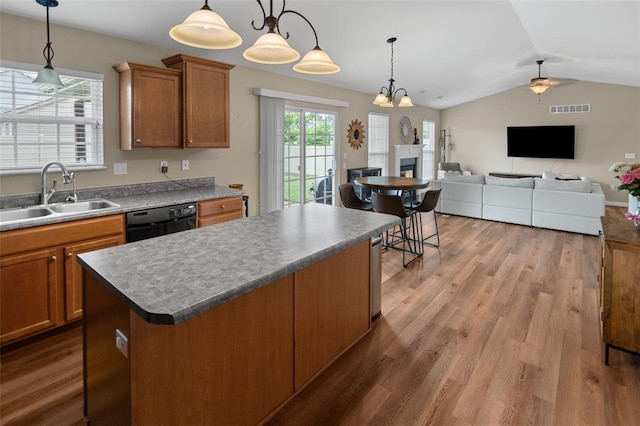 kitchen featuring a sink, black dishwasher, lofted ceiling, a fireplace, and brown cabinetry