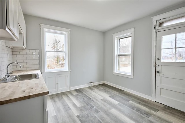 5027 S Broadway Ave Unit 1-4, Saint Louis, MO 63111 - kitchen featuring a sink, backsplash, light wood finished floors, white cabinetry, and baseboards