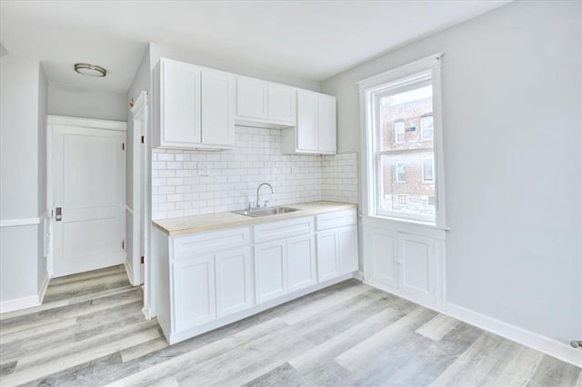 5027 S Broadway Ave Unit 1-4, Saint Louis, MO 63111 - kitchen with a sink, light wood finished floors, light countertops, white cabinets, and backsplash