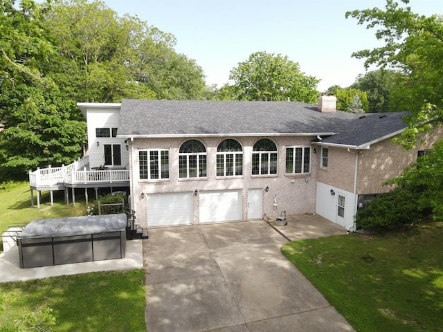 16 Siesta Dr, Hannibal, MO 63401 - back of property featuring an attached garage, concrete driveway, a chimney, roof with shingles, and a lawn
