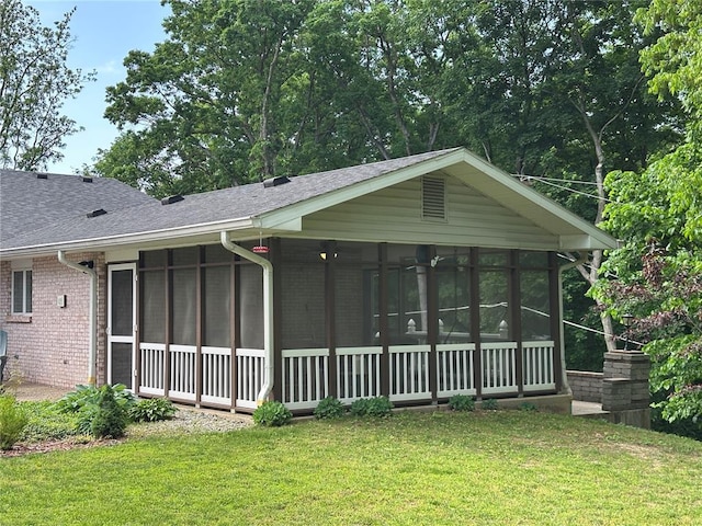 16 Siesta Dr, Hannibal, MO 63401 - rear view of house featuring a sunroom, brick siding, roof with shingles, and a lawn