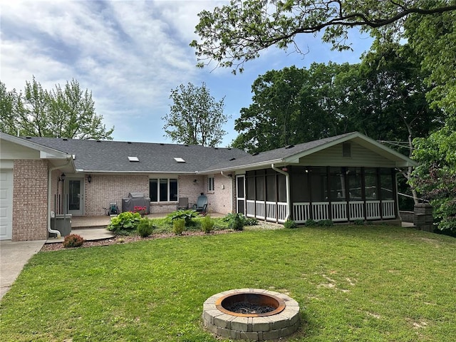 16 Siesta Dr, Hannibal, MO 63401 - back of property with a sunroom, brick siding, a fire pit, and a lawn