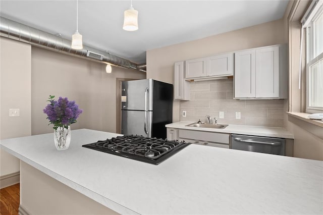4932 Mardel, Saint Louis, MO 63109 - kitchen featuring appliances with stainless steel finishes, a sink, decorative backsplash, light countertops, and decorative light fixtures