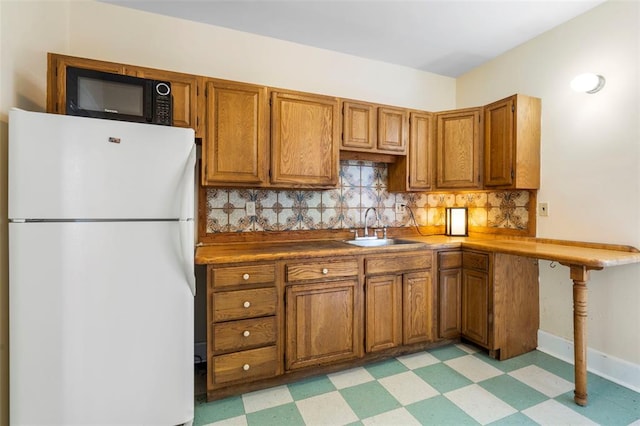 7511 Milan Ave, University City, MO 63130 - kitchen featuring freestanding refrigerator, a sink, light floors, and black microwave