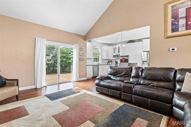 113 Riverwalk Dr, Desloge, MO 63628 - living room featuring wood finished floors, a textured wall, baseboards, high vaulted ceiling, and a chandelier
