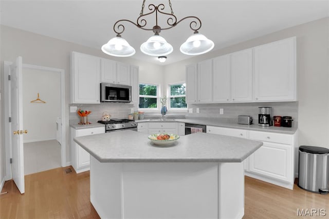 2654 Breckenridge Cir, Ofallon, MO 63368 - kitchen with appliances with stainless steel finishes, decorative backsplash, light countertops, light wood finished floors, and white cabinetry