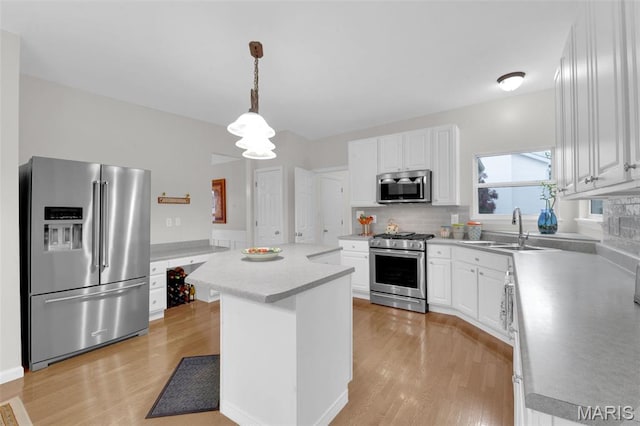2654 Breckenridge Cir, Ofallon, MO 63368 - kitchen with appliances with stainless steel finishes, a sink, light wood-style floors, a kitchen island, and tasteful backsplash