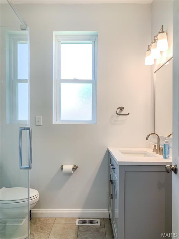 526 State St, Dupo, IL 62239 - full bathroom featuring vanity, toilet, baseboards, and a shower with shower door