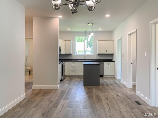 526 State St, Dupo, IL 62239 - kitchen with a chandelier, a sink, dark countertops, white cabinets, and light wood-style flooring
