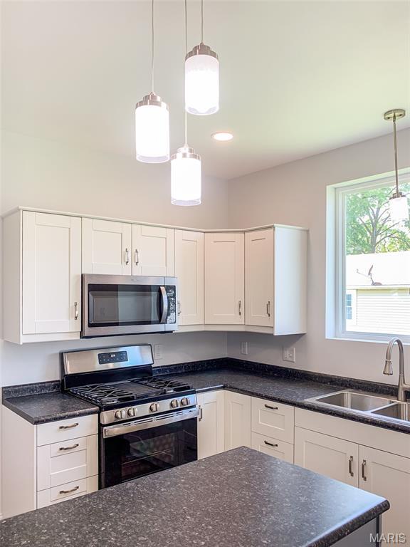 526 State St, Dupo, IL 62239 - kitchen featuring stainless steel appliances, a sink, white cabinetry, pendant lighting, and dark stone counters