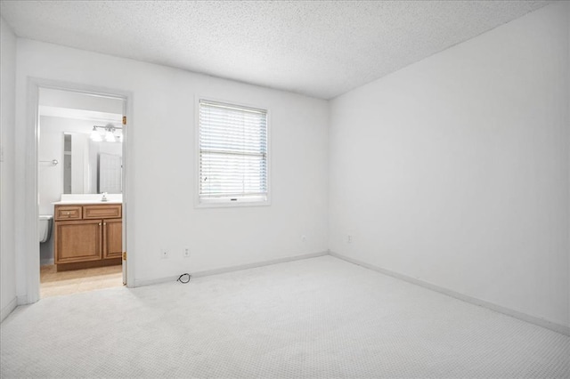 1721 Blue Jay Cv, Saint Louis, MO 63144 - unfurnished bedroom with light colored carpet, a textured ceiling, baseboards, a sink, and ensuite bath