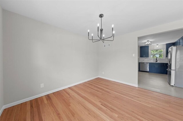 1865 Shardell Dr, Spanish Lake Township, MO 63138 - unfurnished room featuring a chandelier, light wood-style flooring, a sink, and baseboards
