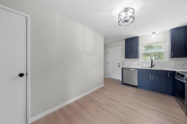 1865 Shardell Dr, Spanish Lake Township, MO 63138 - kitchen featuring stainless steel appliances, a sink, blue cabinetry, light countertops, and light wood finished floors